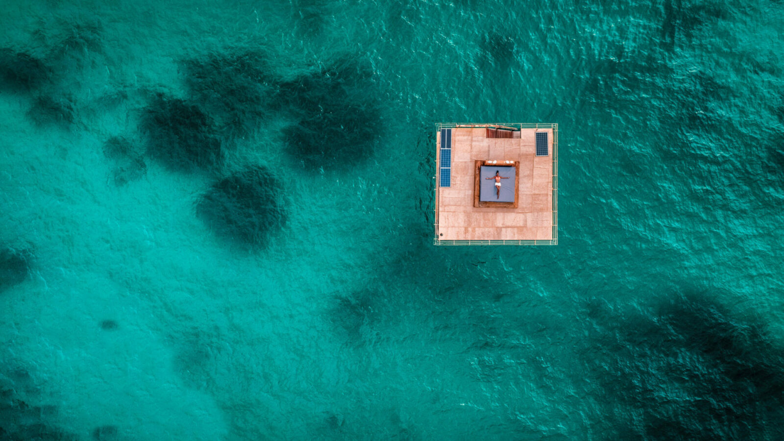 Image of the floating underwater room at Manta Resort on Pemba Island, Tanzania from overhead. Guest can be seen relaxing on a top-level sun tanning bed | TrueAfrica Safaris | Blog | Kwanini: The Manta Resort