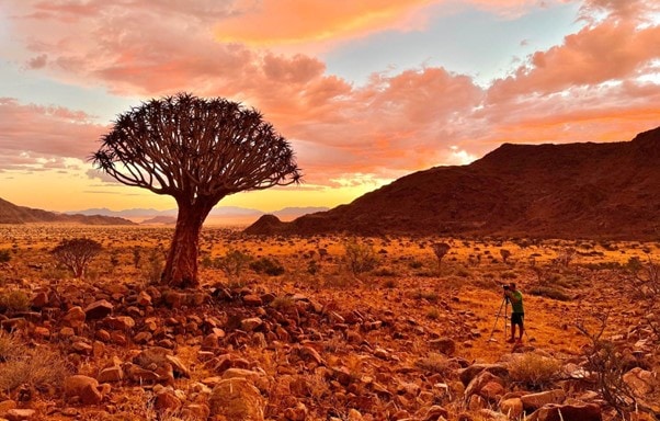 a man in a rocky namibian landscape photographing the landscape