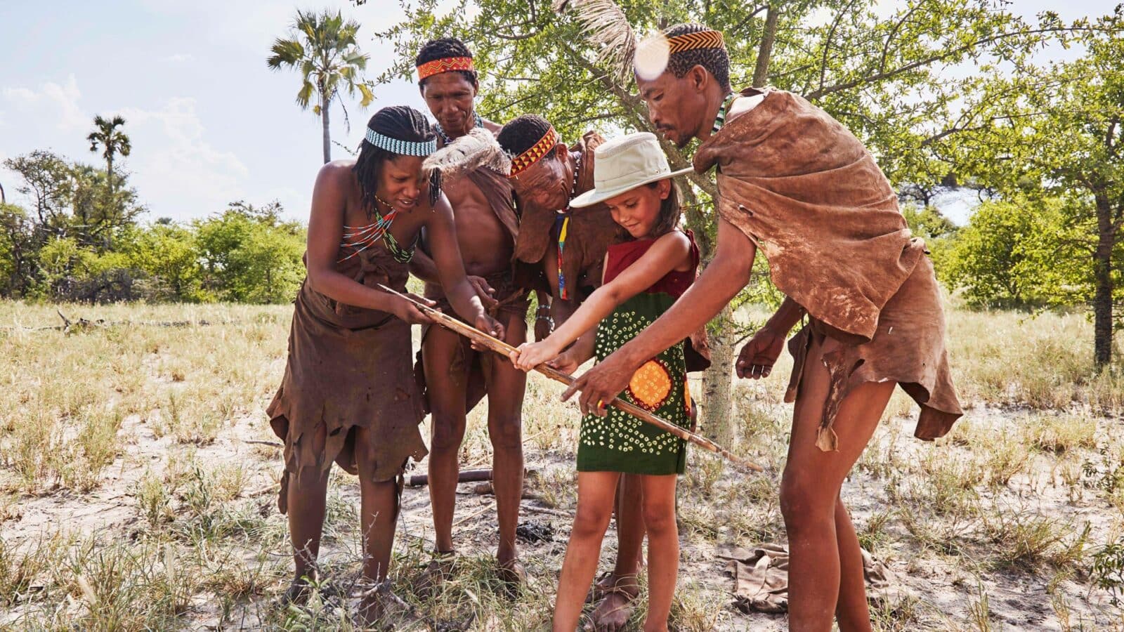 Bushmen showing a little girl how to shoot a bow and arrow on nature walk
